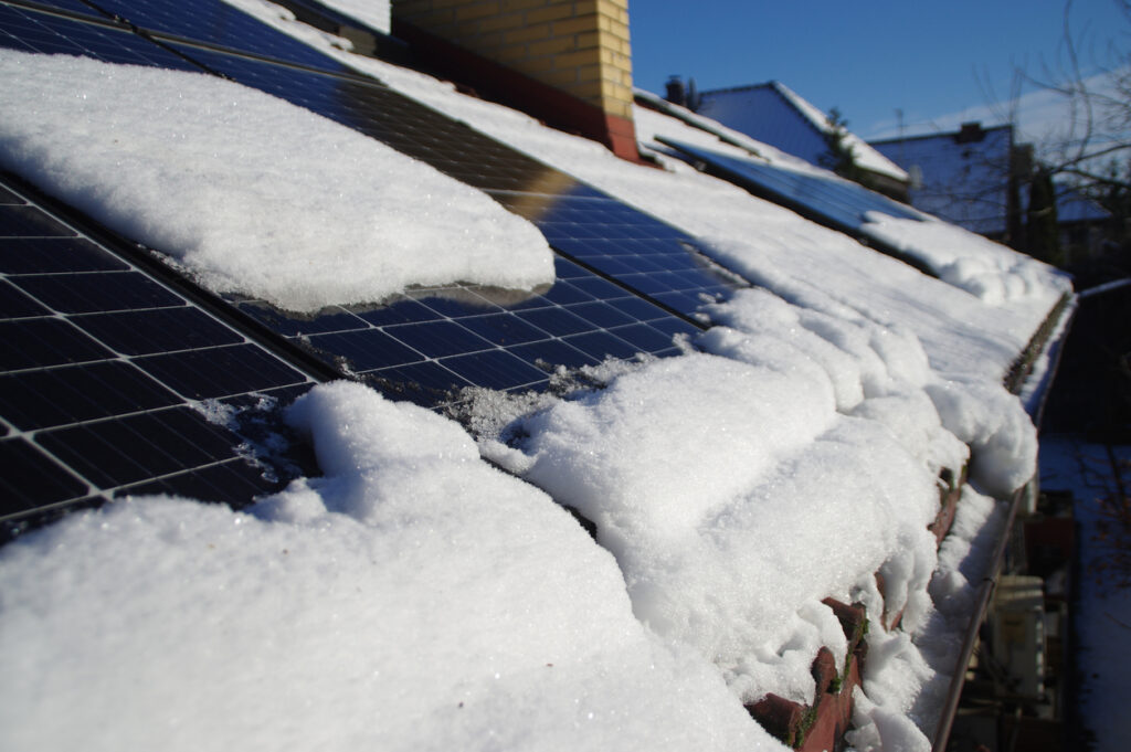 snow covered solar panels on house roof